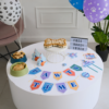 Pet-themed birthday table with paw-print balloons, a bone-shaped cake on a cake stand, bowls of cookies, and PAWTIME bunting.