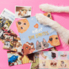 Flat lay: blue dog-themed book titled 'amor sin límites' on a pink surface, surrounded by dog photos and fluffy white paws around it.