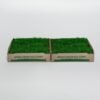 Two green artificial grass samples in open-top cardboard boxes labeled www.pipigrass.com on a white background.