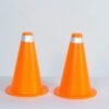 Two bright orange traffic cones with reflective bands standing side by side on a light surface.