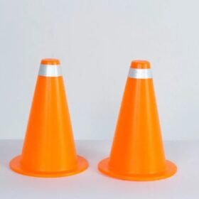 Two bright orange traffic cones with reflective bands standing side by side on a light surface.