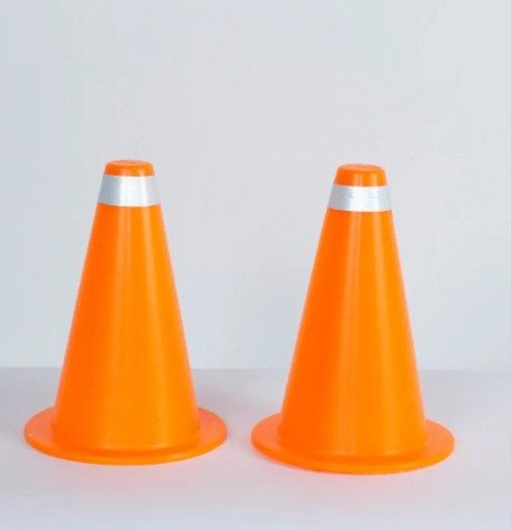 Two bright orange traffic cones with reflective bands standing side by side on a light surface.