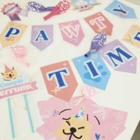 Pastel birthday party decorations on a white table with letter cards, ribbons, and a cat sticker nearby.