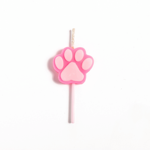 Pink paw-print candle placed on a white candle stick against a white background, isolated.